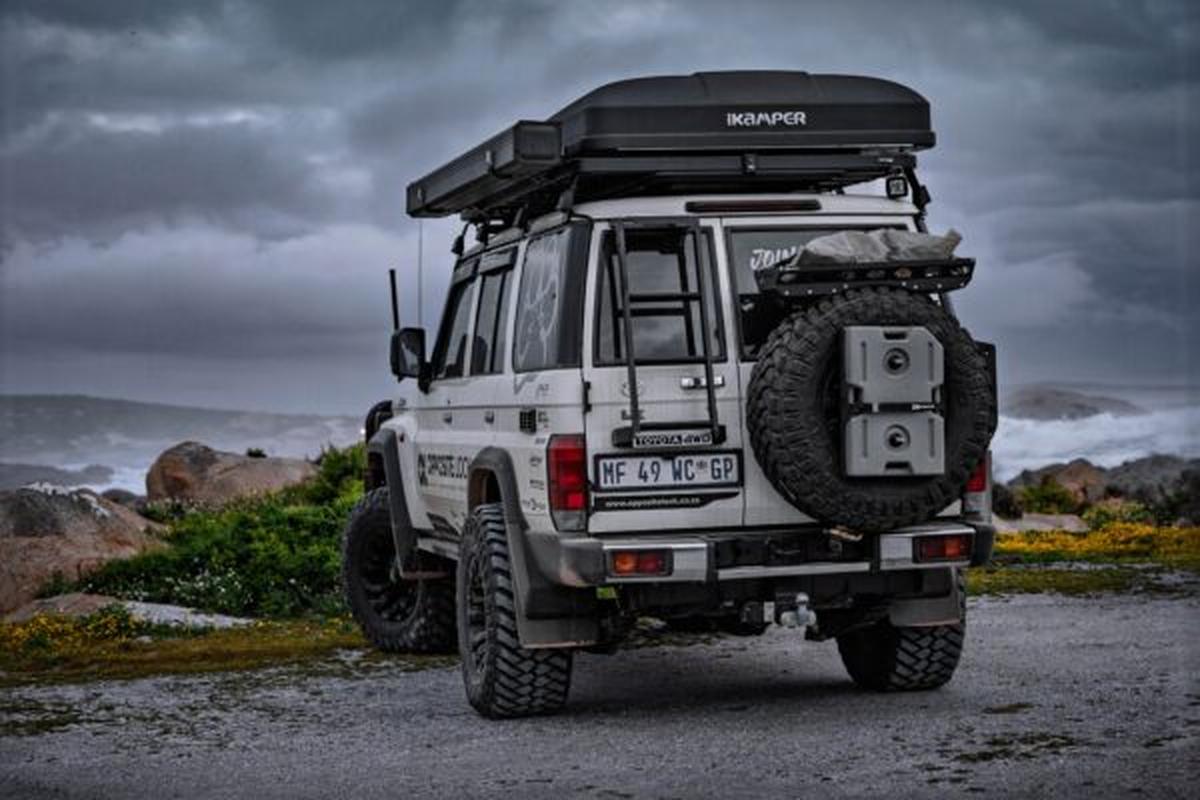A loaded 79 Series with a rooftop tent, parked on the coast